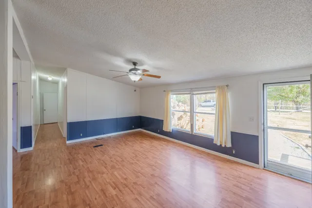 a view of an empty room with a window and wooden floor