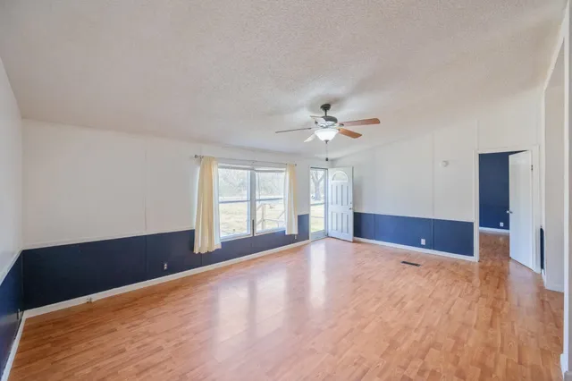 a view of an empty room with window and wooden floor