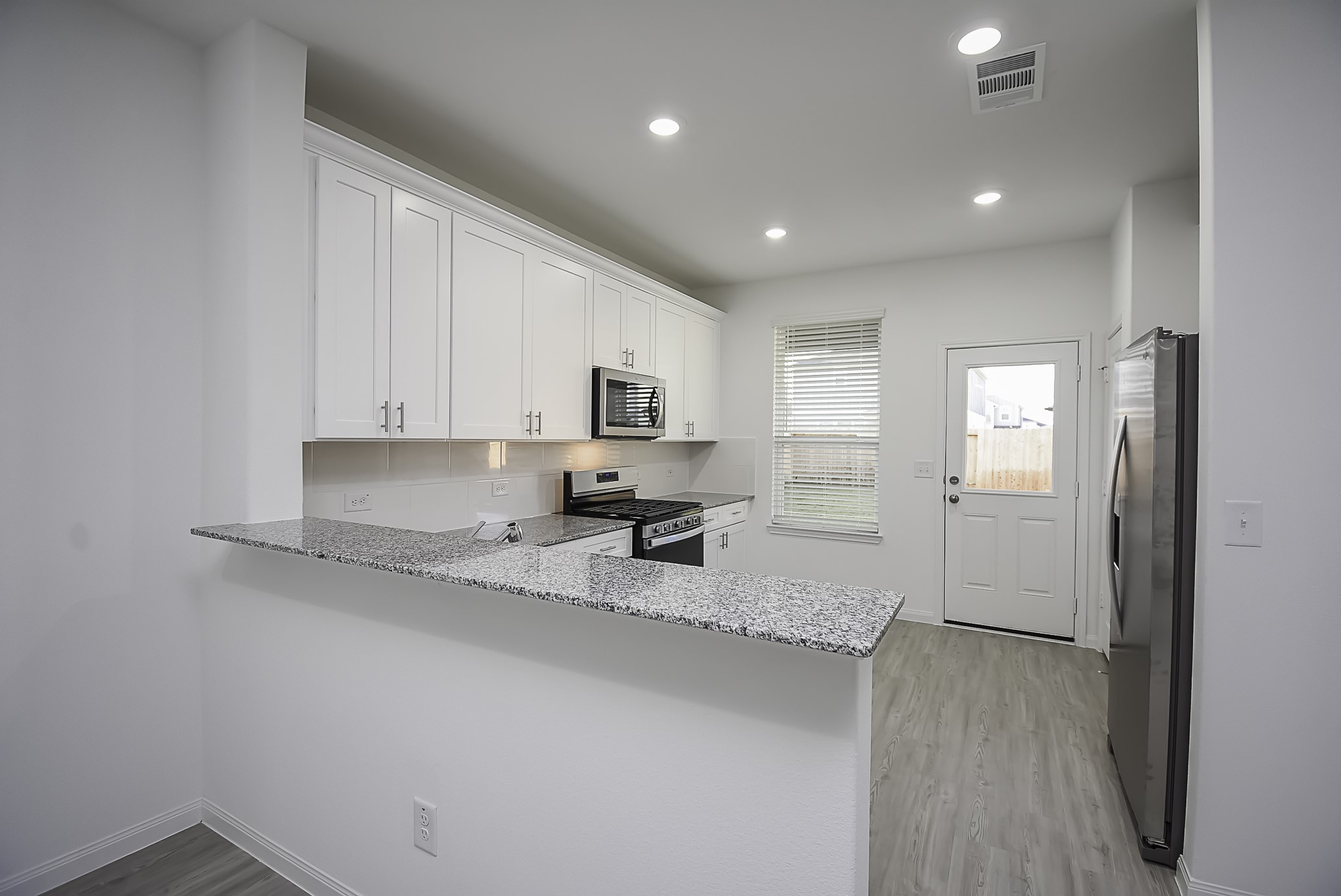 23407 Honey Spade Road Hockley, TX 77447 - Photo 6 of 34 a kitchen with granite countertop white cabinets and stainless steel appliances