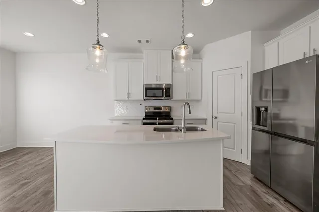 a kitchen with kitchen island a counter space a refrigerator and cabinets