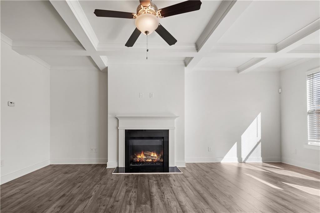 7690 Baron Road Fairburn, GA 30213 - Photo 15 of 29 an empty room with windows a fireplace a ceiling fan and wooden floor