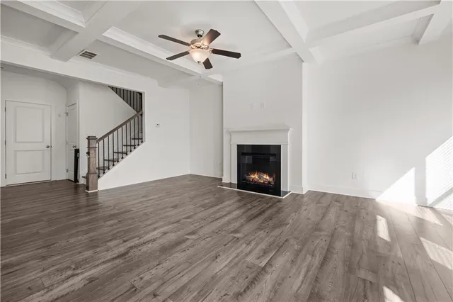 a view of an empty room with wooden floor and a fireplace