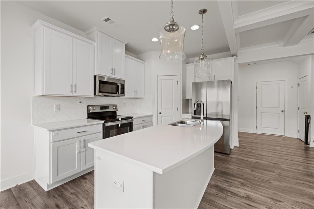 7690 Baron Road Fairburn, GA 30213 - Photo 7 of 29 a large kitchen with kitchen island a sink stainless steel appliances and cabinets