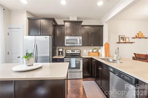a kitchen with stainless steel appliances granite countertop a sink a stove and refrigerator