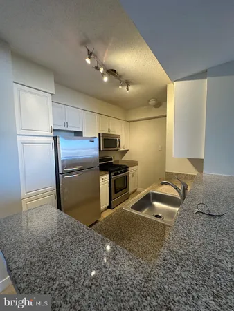 a kitchen with kitchen island granite countertop a sink refrigerator and cabinets