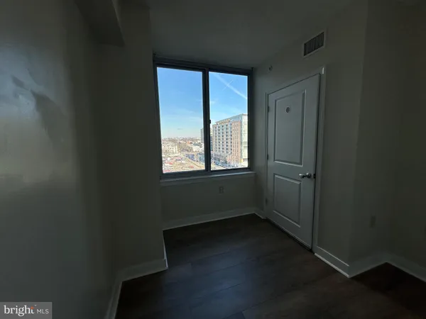 an empty room with wooden floor and windows