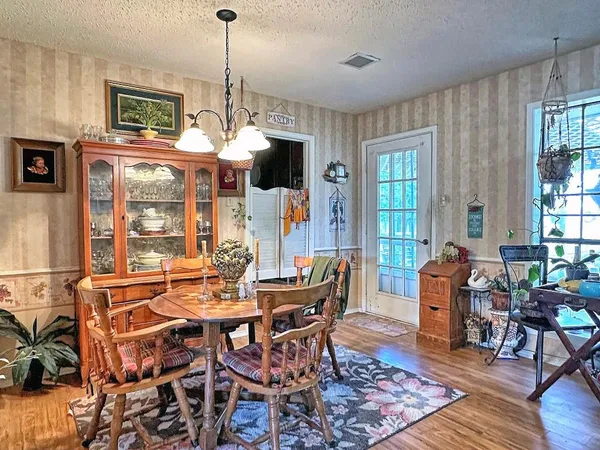 a dining room with wooden floor a chandelier a wooden table and chairs