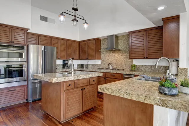 a kitchen with stainless steel appliances granite countertop a sink refrigerator and cabinets