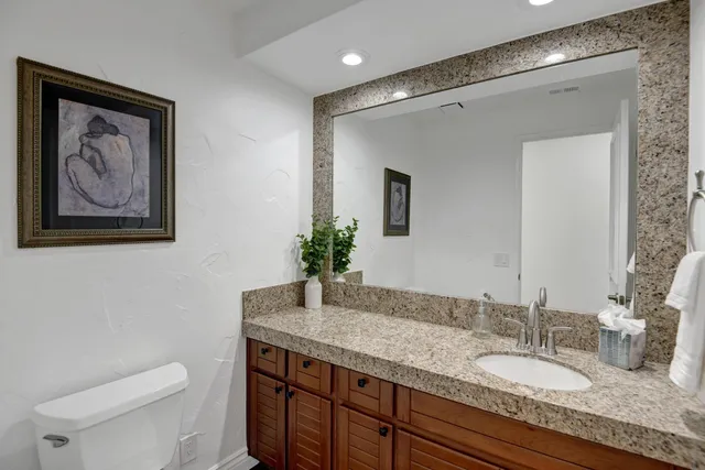 a bathroom with a granite countertop sink a toilet and mirror