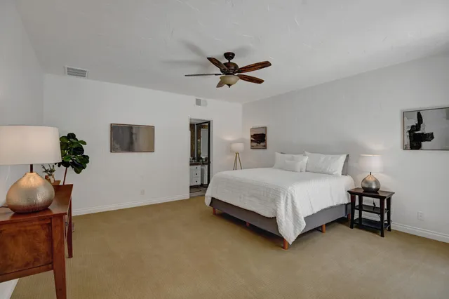 a spacious bedroom with a bed and a chandelier fan
