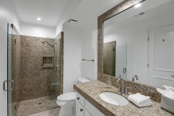 a bathroom with a granite countertop sink toilet and shower