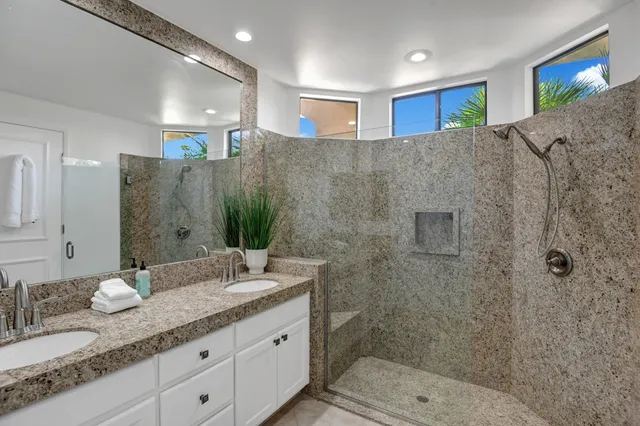 a bathroom with a granite countertop sink a toilet a mirror and shower