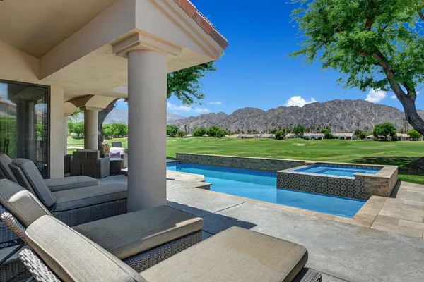 a view of a patio with couches table and chairs under an umbrella