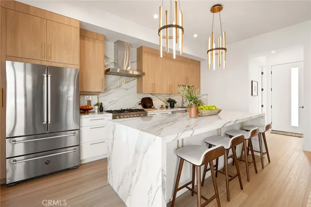 a kitchen with stainless steel appliances granite countertop a refrigerator a sink dishwasher a stove and a refrigerator with wooden floor