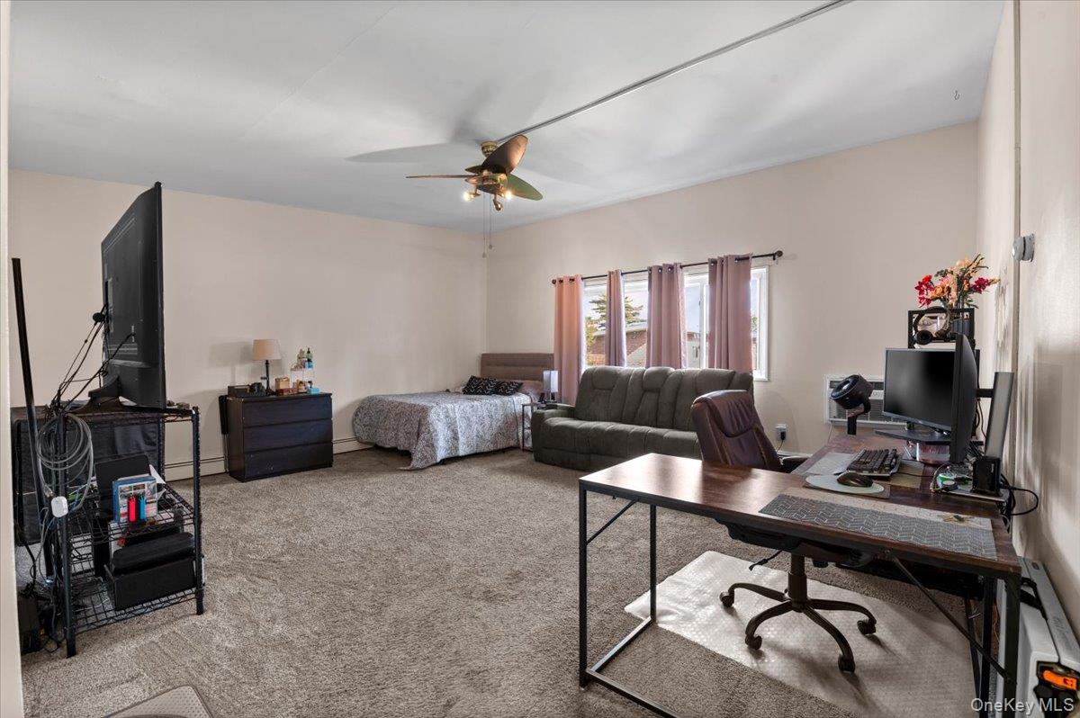 267 North Newbridge Road, Unit 2D Levittown, NY 11756 - Photo 4 of 22 Spacious room featuring neutral carpeting, a ceiling fan, multiple windows with natural light, and ample wall space