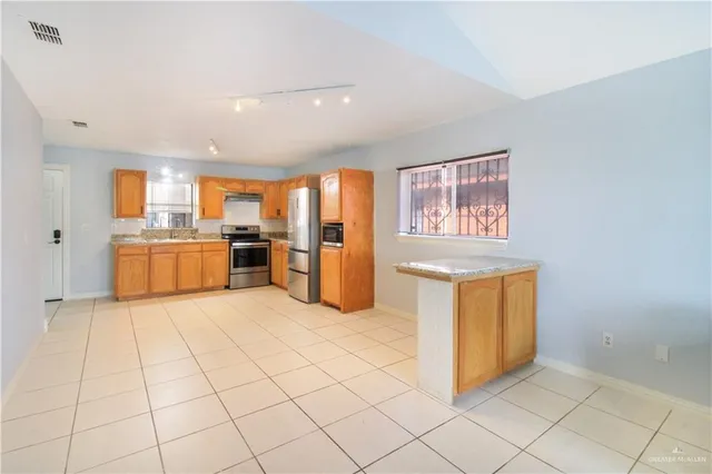 a view of kitchen with granite countertop cabinets and refrigerator