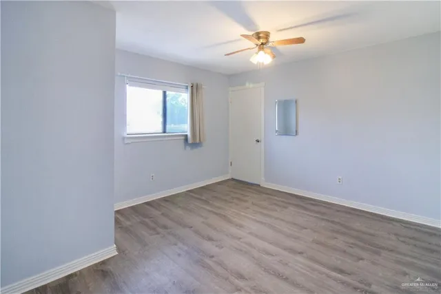an empty room with a window and a fan
