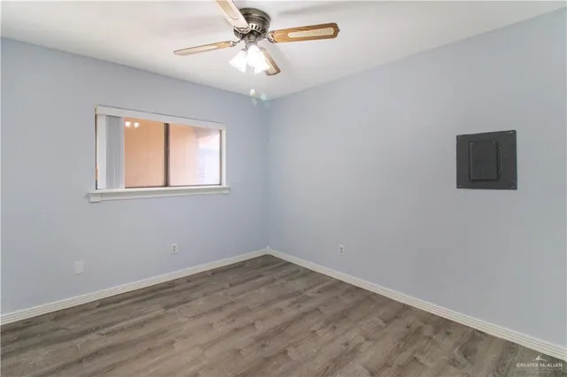 a view of empty room with wooden floor and fan