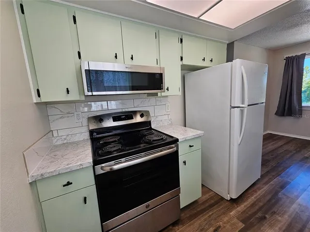 a kitchen with a stove a refrigerator and a wooden floor