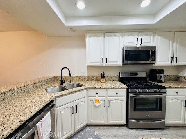 4969 Embassy Way, Unit 6 Cypress, CA 90630 - Photo 8 of 19 a kitchen with granite countertop a stove top oven a sink and dishwasher with wooden floor