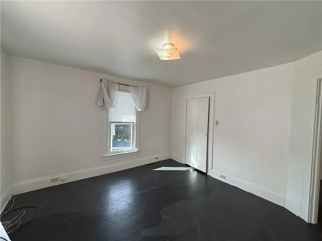 an empty room with a window and wooden floor