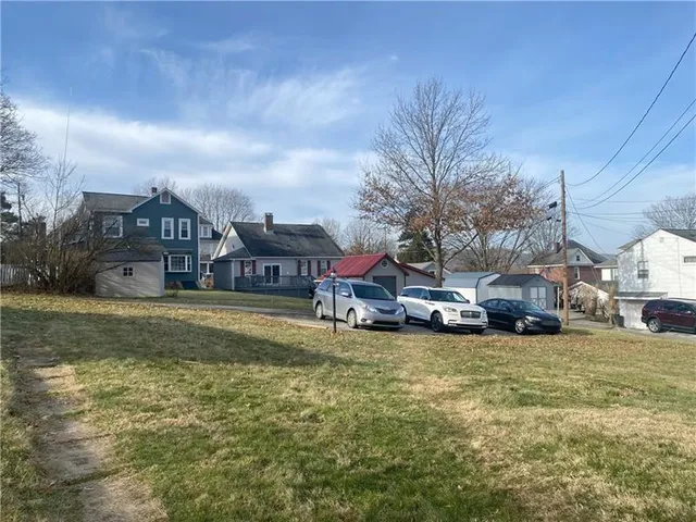 a view of a house with a big yard and large trees