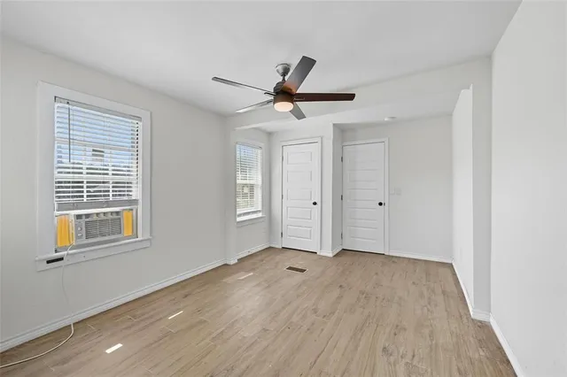 a view of empty room with wooden floor and fan