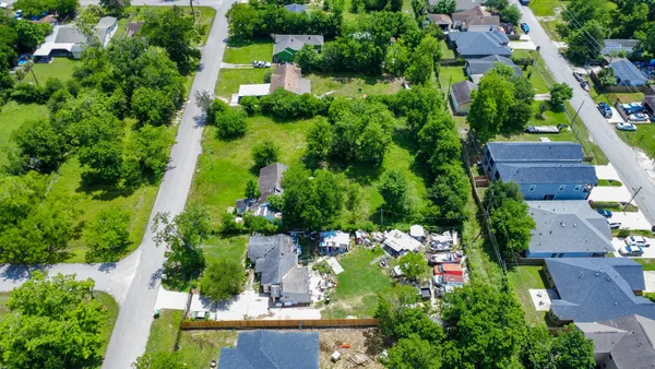 an aerial view of residential houses with outdoor space and trees all around