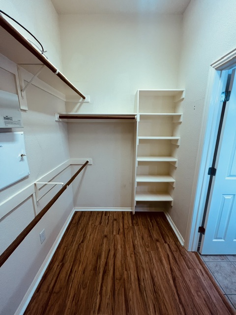 20724 Kearney Hill Road Pflugerville, TX 78660 - Photo 26 of 40 Walk-in closet featuring wood-finish flooring, built-in shelving, and multiple hanging rods
