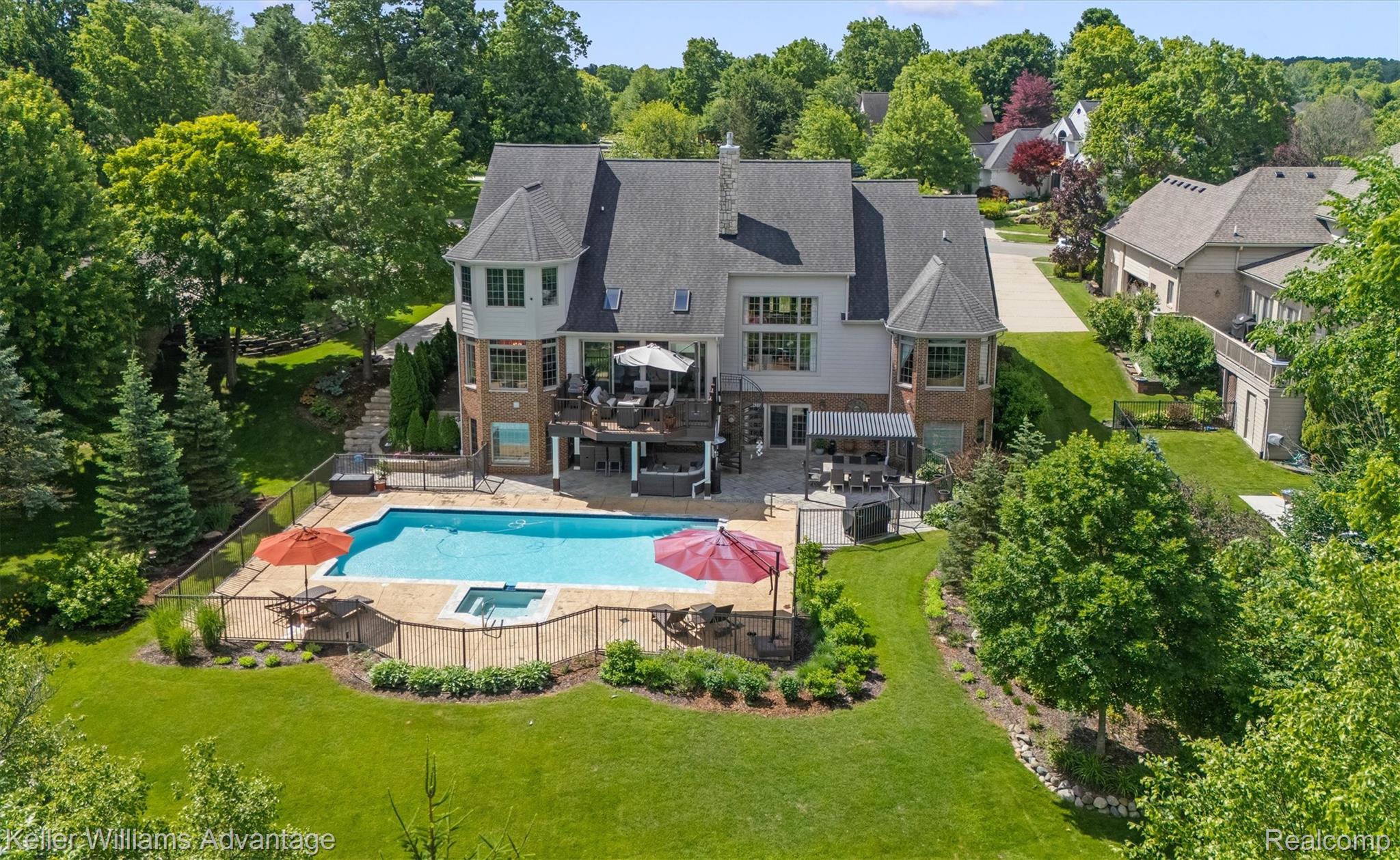 22878 Tree Top Court South Lyon, MI 48178 - Photo 45 of 75 Expansive rear exterior featuring a fenced in-ground pool, integrated spa, and a multi-level deck