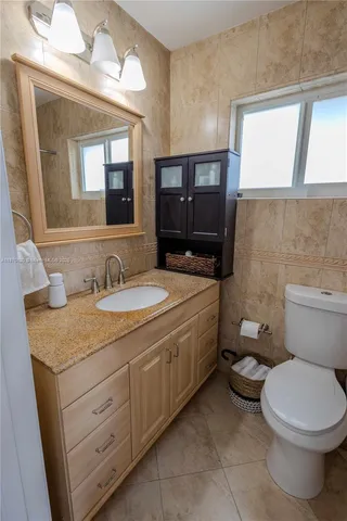 a bathroom with a granite countertop toilet sink and mirror