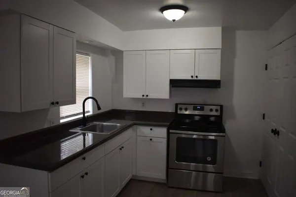 a kitchen with granite countertop white cabinets and black appliances