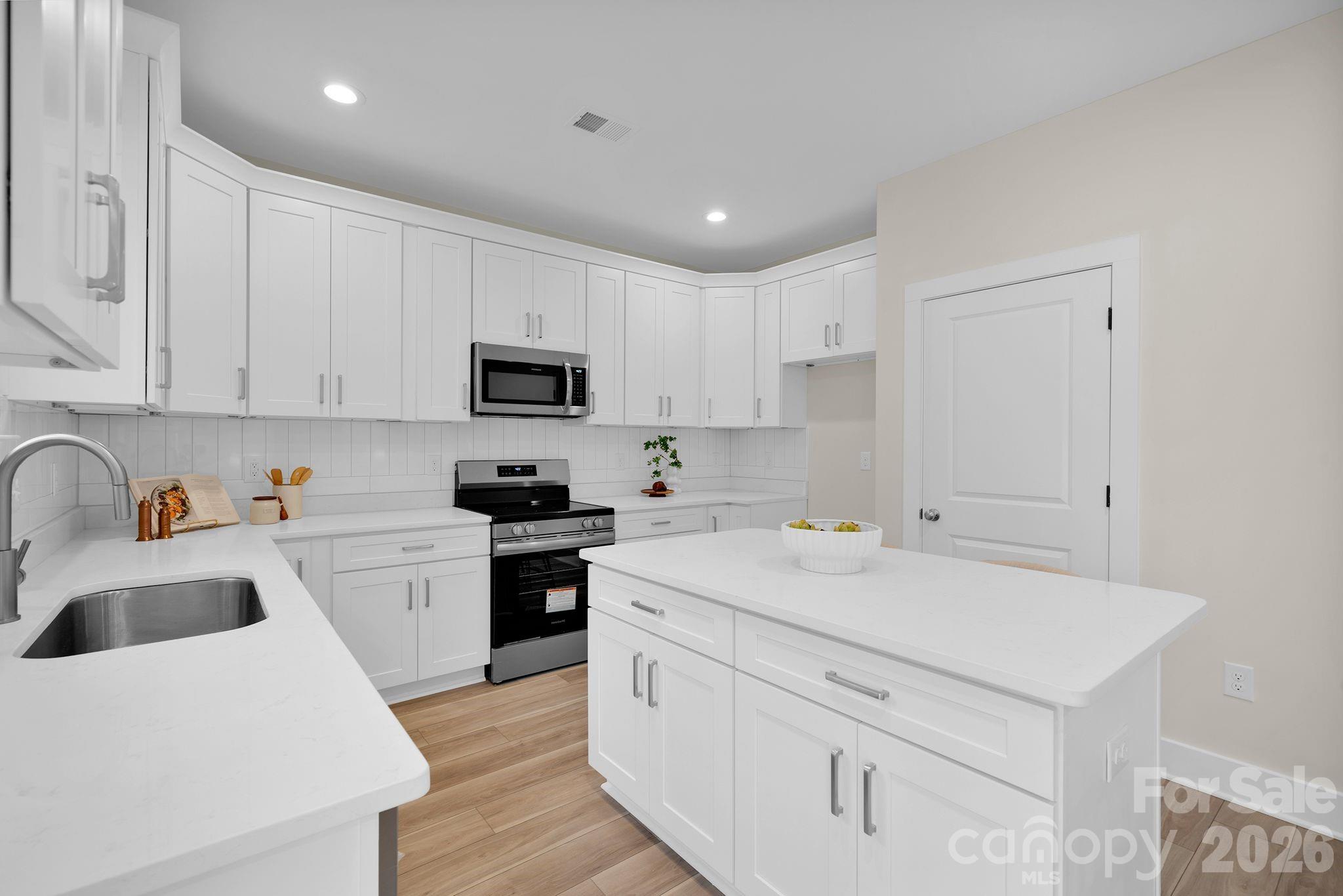 9022 Unity Church Road Mooresville, NC 28115 - Photo 7 of 22 a kitchen with a sink a stove a refrigerator and white cabinets