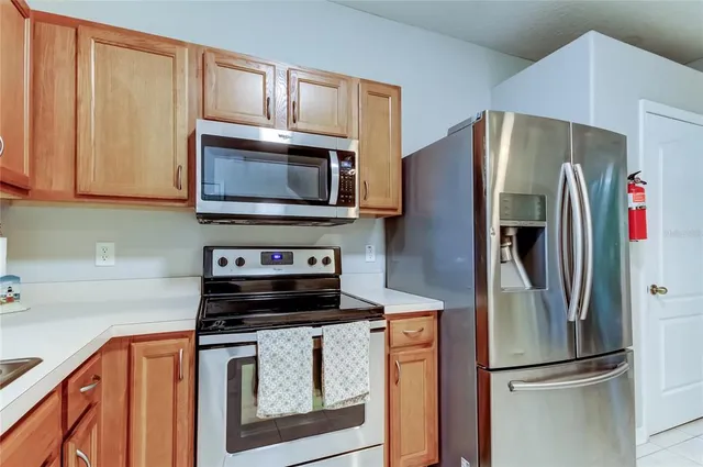 a kitchen with stainless steel appliances granite countertop a refrigerator a sink dishwasher and a stove with wooden floor