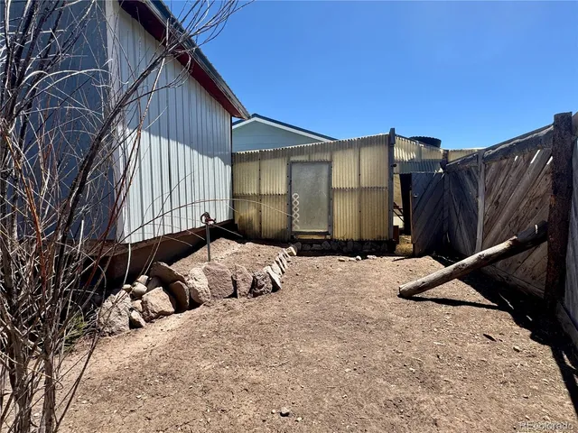 a backyard of a house with large trees and outdoor seating