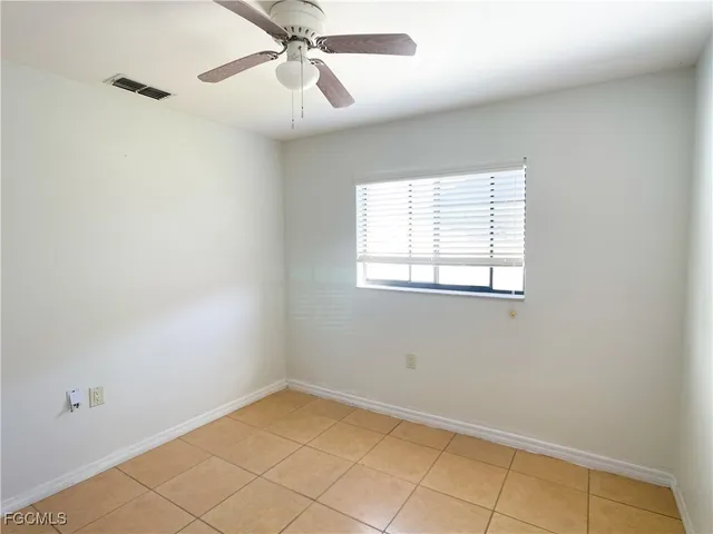 an empty room with a window and a fan