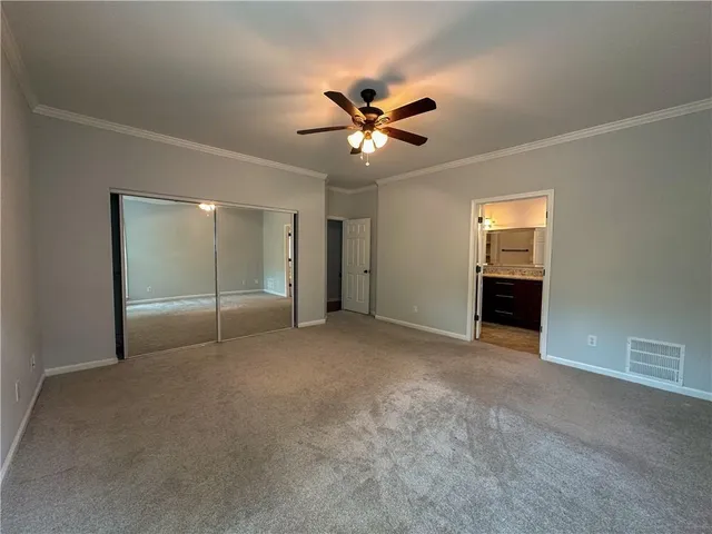an empty room with closet and a ceiling fan