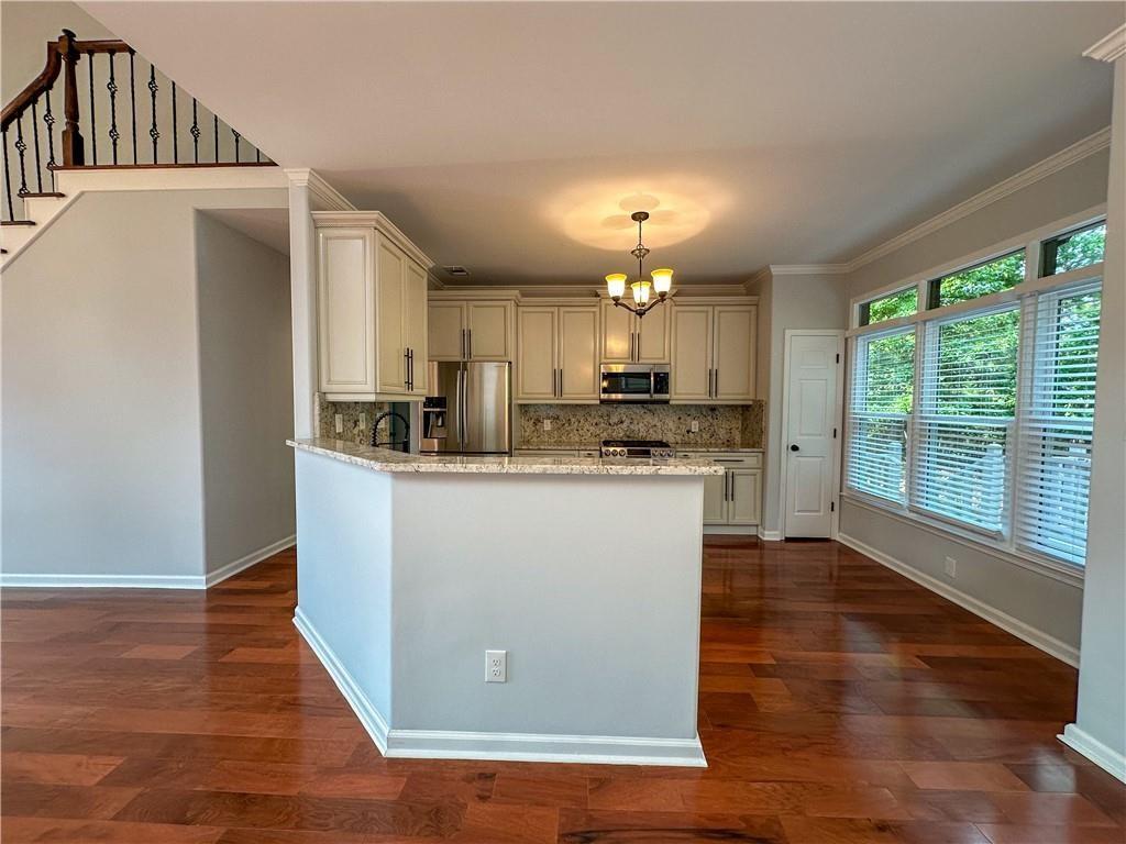 3255 Park Chase Alpharetta, GA 30022 - Photo 6 of 27 a kitchen with kitchen island granite countertop a stove a sink a refrigerator and a counter space