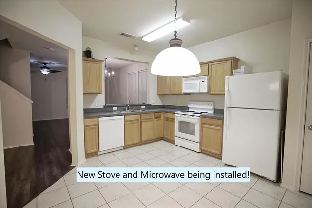 a large white kitchen with a refrigerator a stove a sink dishwasher a oven a dining table and chairs