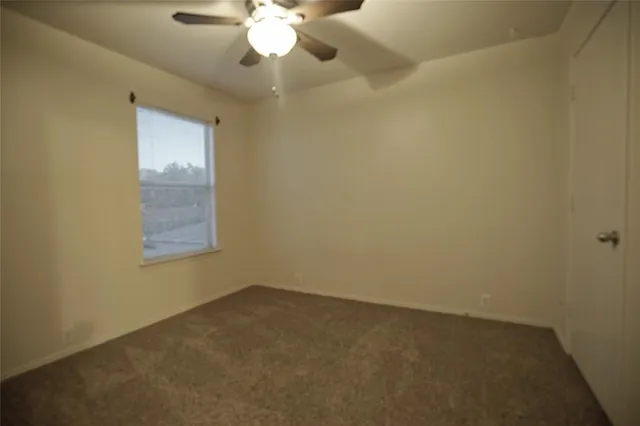 an empty room with a chandelier fan and a window