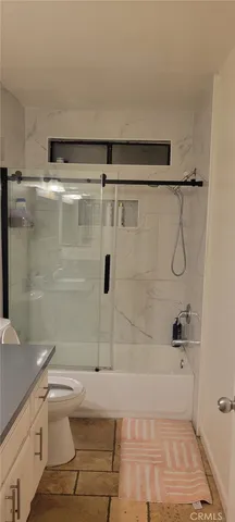 a bathroom with a granite countertop bathtub shower and toilet