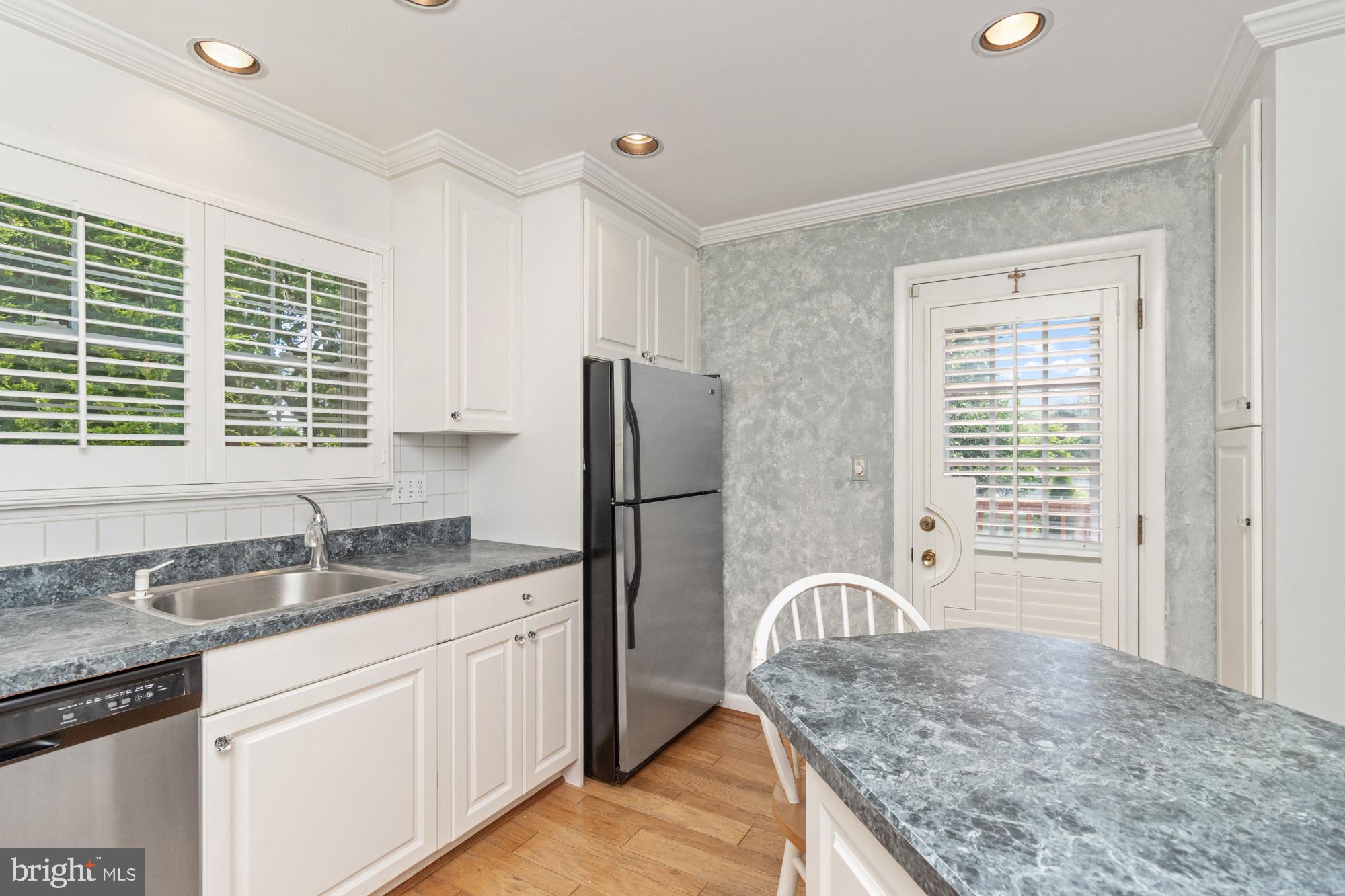1429 Adamsview Road Baltimore, MD 21228 - Photo 13 of 44 a kitchen with granite countertop a sink dishwasher a refrigerator and wooden cabinets