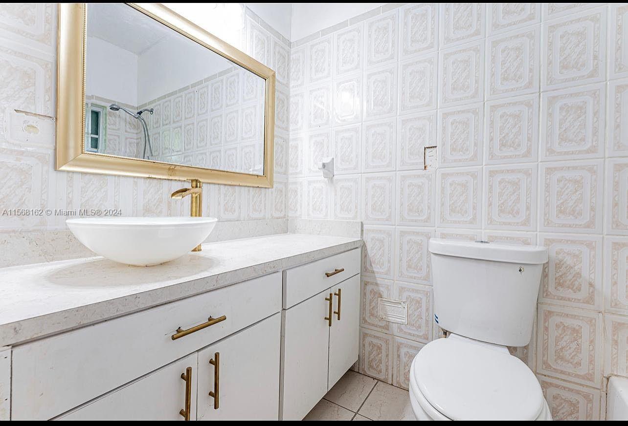 2320 Northwest 52nd Street, Unit A Miami, FL 33142 - Photo 5 of 8 a bathroom with a toilet a sink and mirror