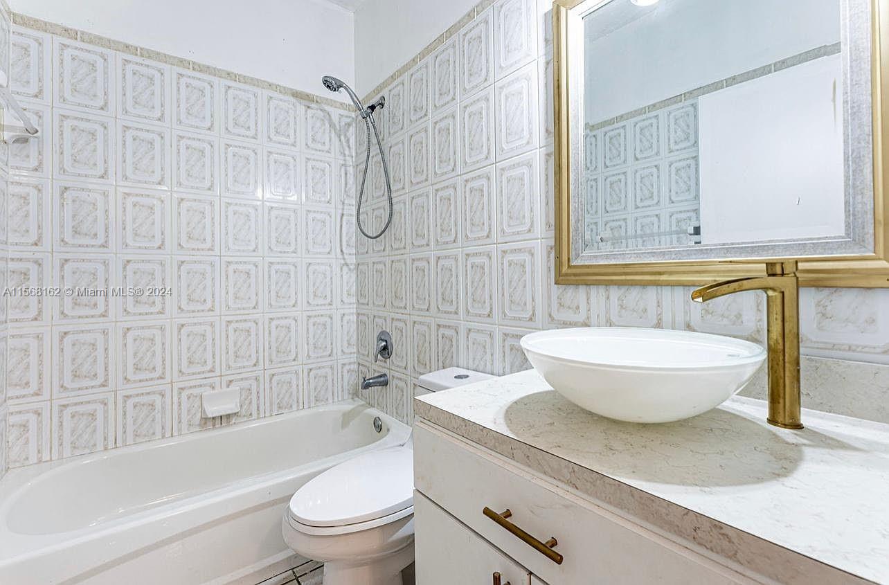 2320 Northwest 52nd Street, Unit A Miami, FL 33142 - Photo 6 of 8 a bath room with a toilet a bath tub and a shower