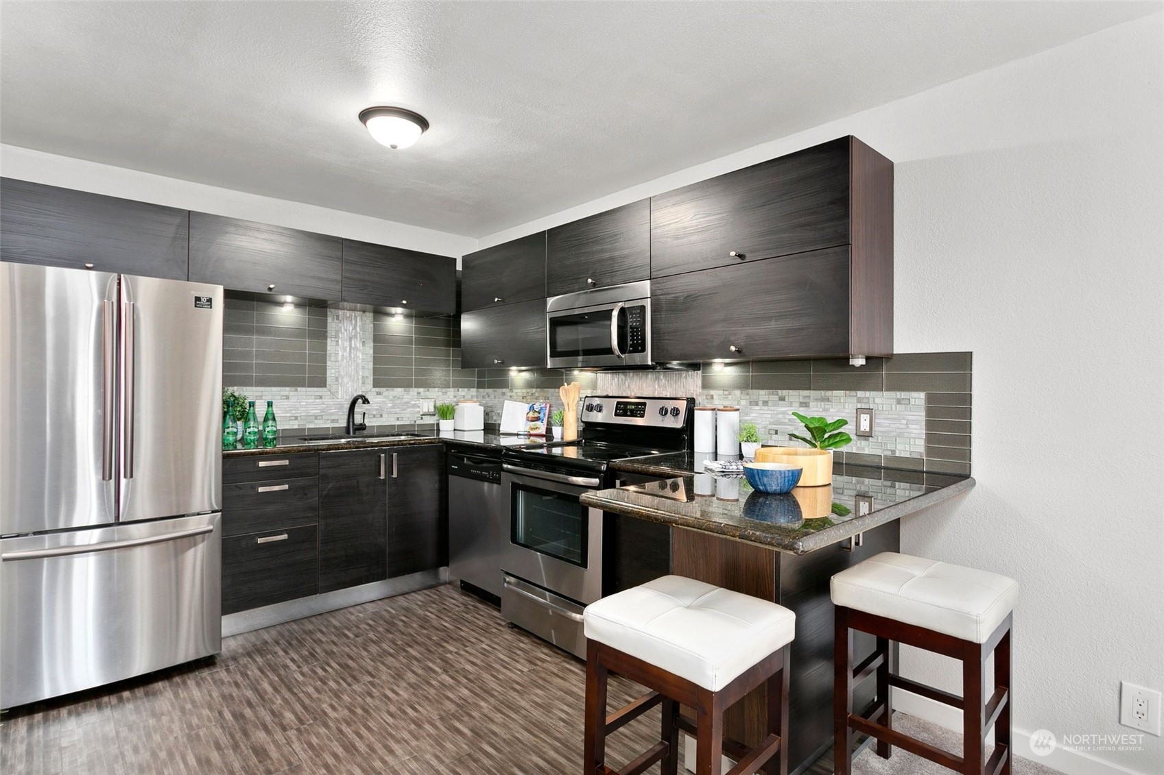 1425 South Puget Drive, Unit 308 Renton, WA 98055 - Photo 4 of 23 a kitchen with stainless steel appliances a refrigerator a stove a sink a stove a dining table and chairs