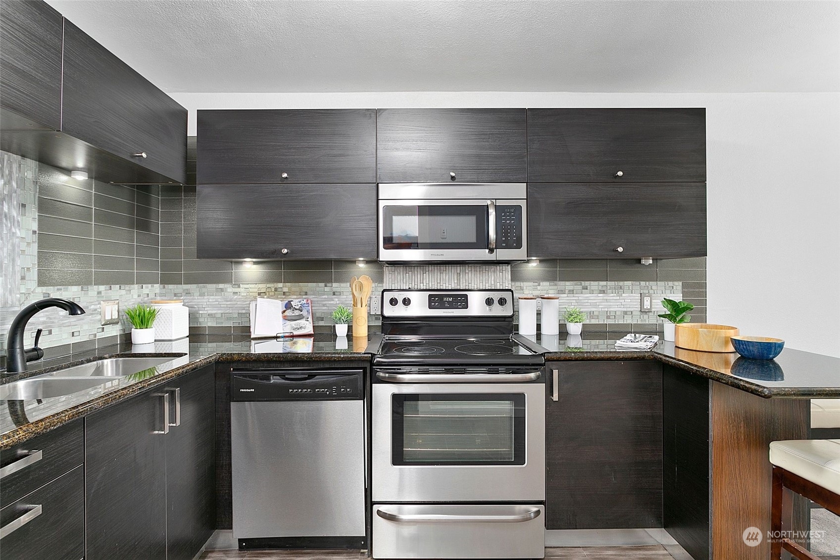 1425 South Puget Drive, Unit 308 Renton, WA 98055 - Photo 5 of 23 a kitchen with kitchen island granite countertop a sink and steel appliances