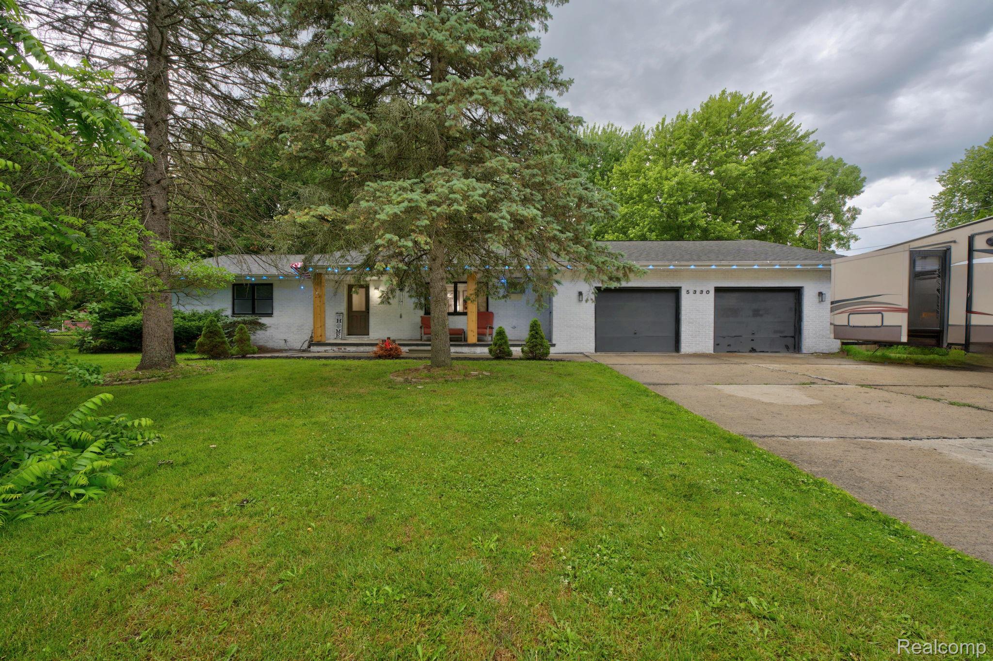 5330 Sheridan Road Saginaw, MI 48601 - Photo 5 of 50 Ranch-style exterior with a two-car garage, concrete driveway, and mature landscaping