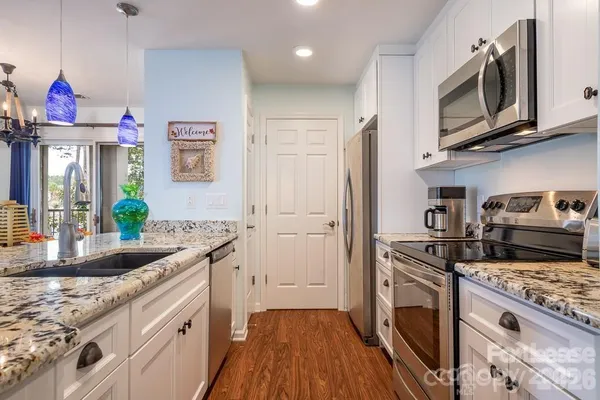 a kitchen with granite countertop a sink dishwasher stove and cabinets