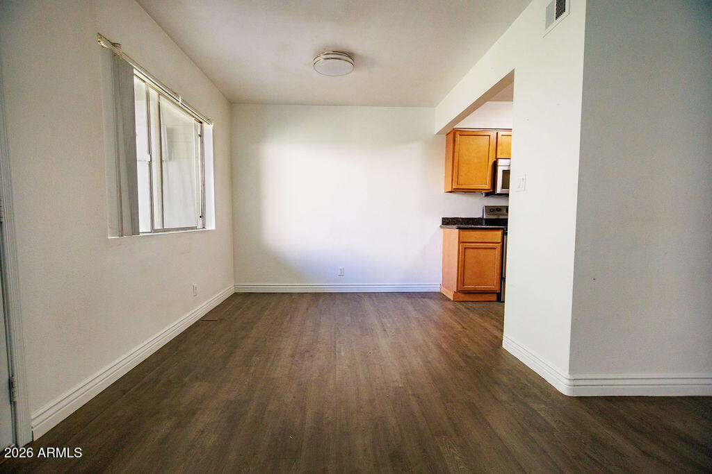 1702 West Tuckey Lane, Unit 103 Phoenix, AZ 85015 - Photo 7 of 13 an empty room with wooden floor and windows