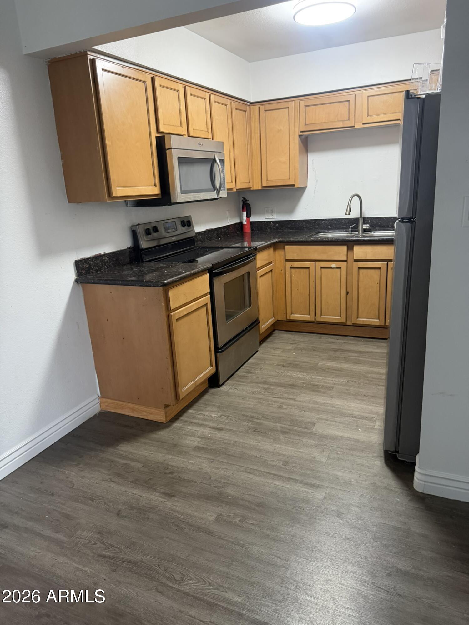 1702 West Tuckey Lane, Unit 103 Phoenix, AZ 85015 - Photo 9 of 13 a kitchen with granite countertop a sink cabinets and stainless steel appliances